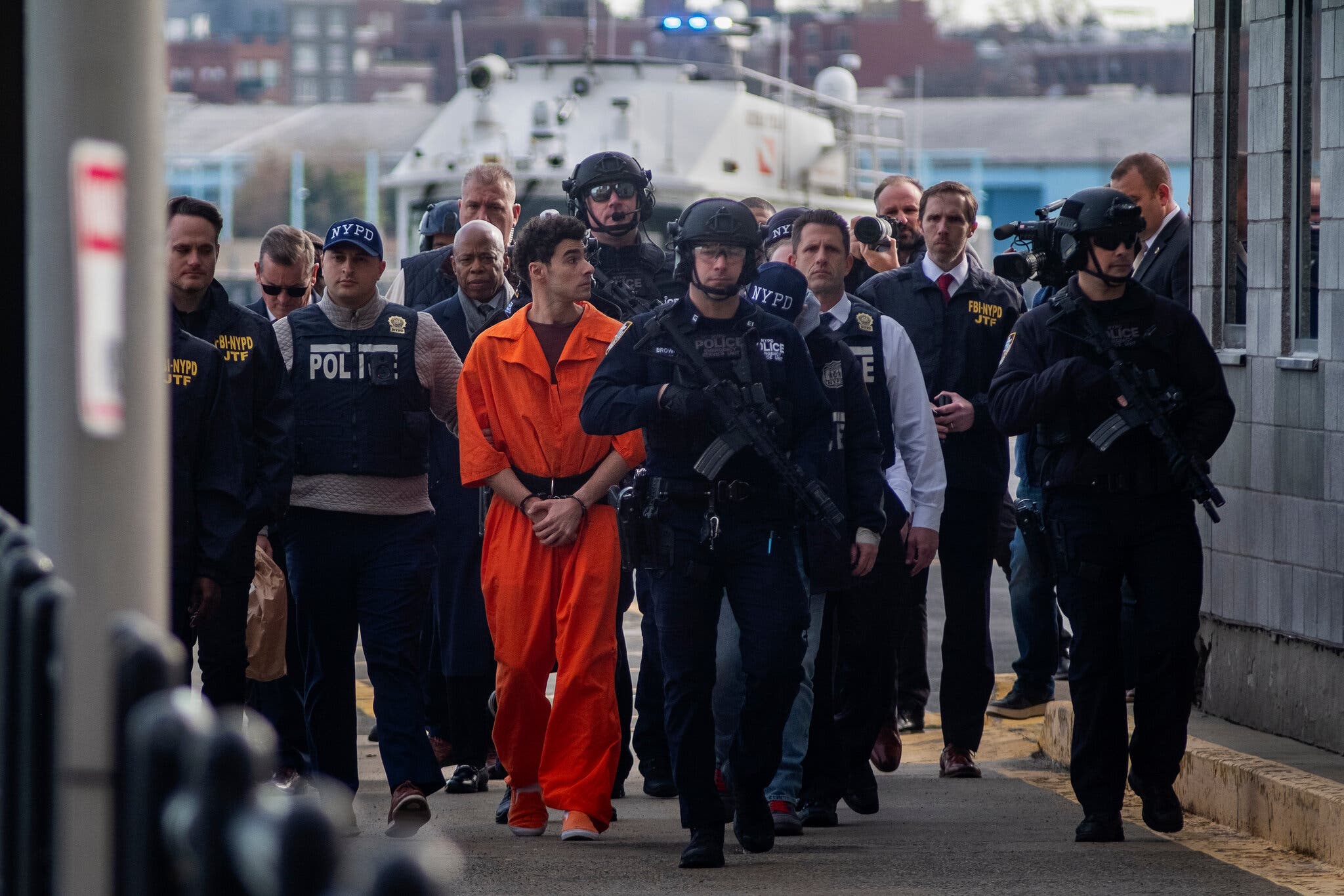 Luigi Mangione was flown from Pennsylvania to New York, where he was guarded by a phalanx of officers and Mayor Eric Adams.Credit...Alan Chin for The New York Times