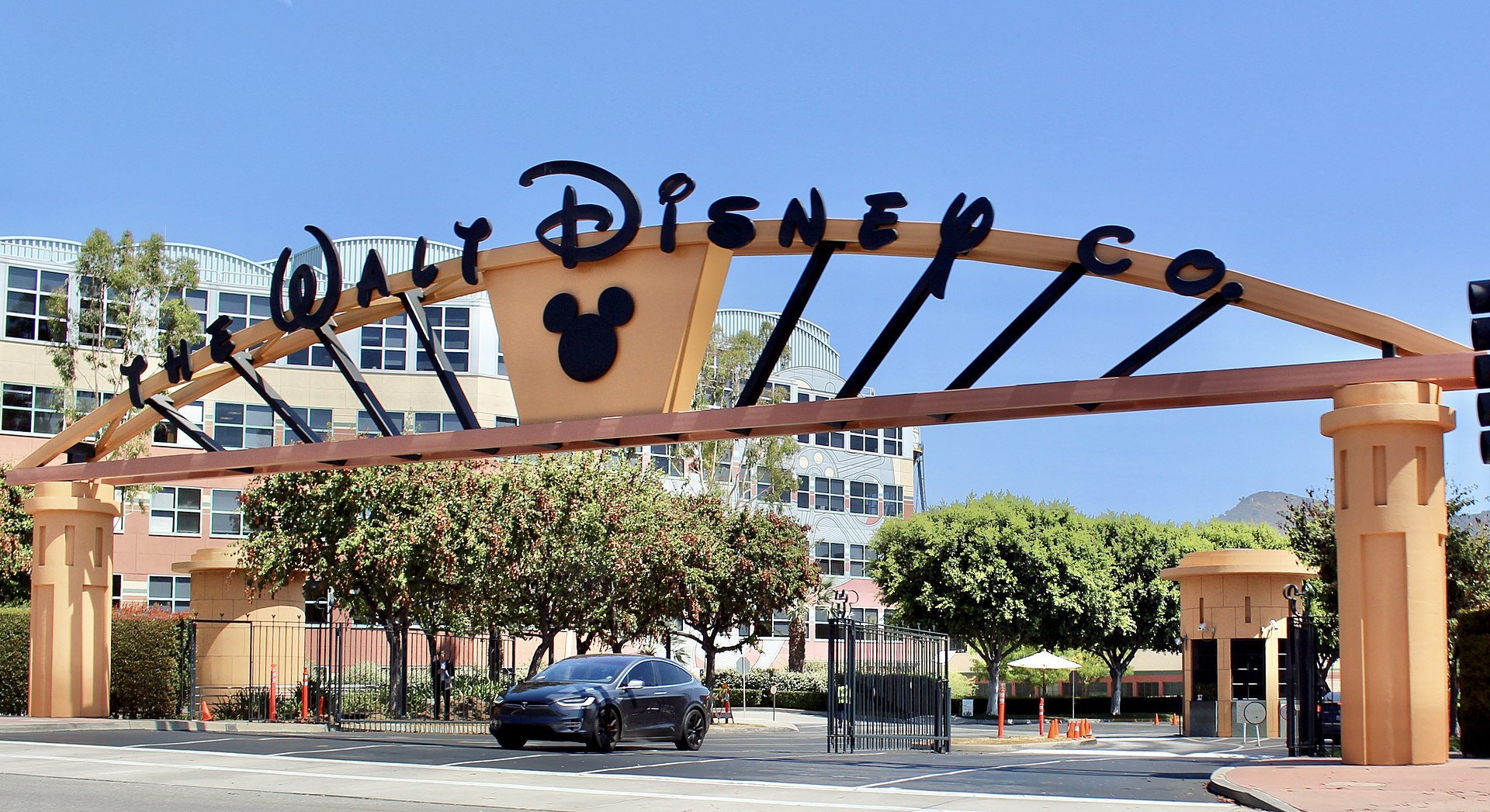 The Alameda Avenue entrance to the Walt Disney Studios in Burbank, California. This was taken just after a major renovation in summer 2016, in which the dated tropical pastels of the gateway arch were replaced with a more conservative orange-and-black color scheme and Mickey Mouse was added to the arch. Photographed on July 11, 2016 by user Coolcaesar.