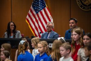 During a visit to the Arizona State Capitol on Tuesday, dozens of school children, several of them waving posters, appeared with the health secretary.Credit...Ash Ponders for The New York Times