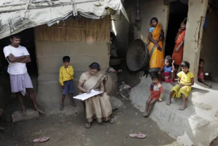 Mahesh Shah, left, stands as his family members look while census worker Rumima Das, writes the information on a paper on the first day of the national census at Ramsingh Chapori village, east of Gauhati, India in 2010. (Anupam Nath/AP)