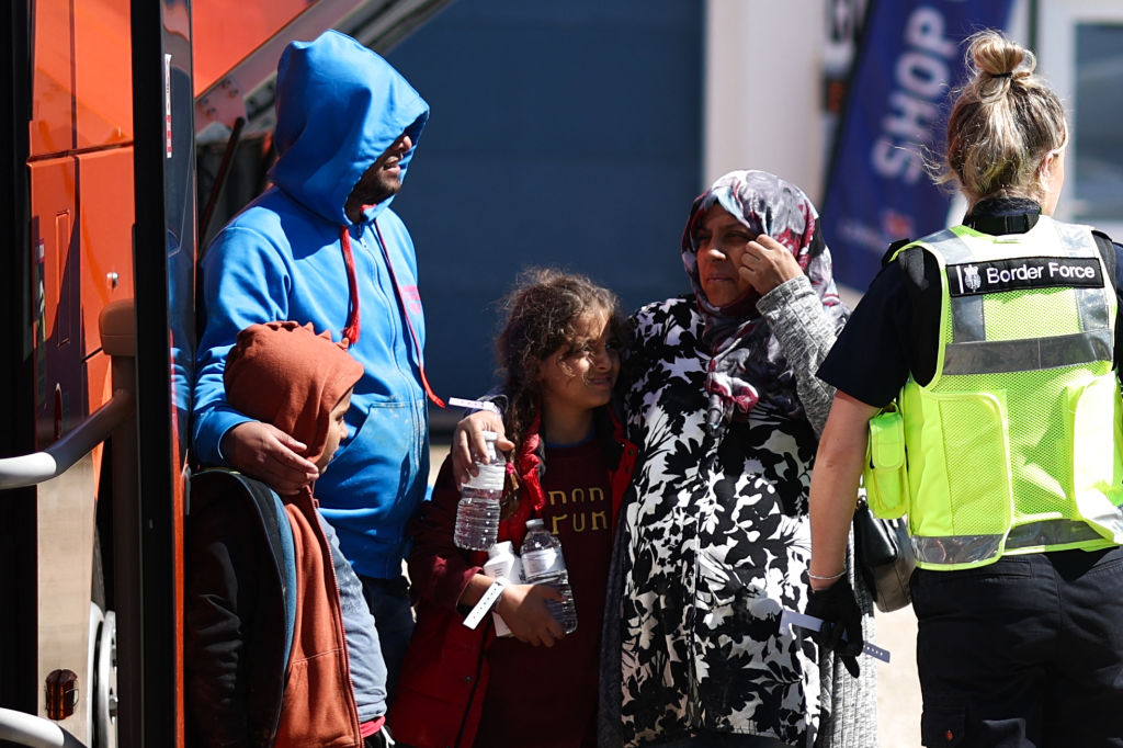 A migrant pregnant woman is helped onto a bus in Dungeness, England, on August 16, 2023. (Henry Nicholls / AFP via Getty Images)