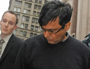 In this Oct. 16, 2009 photo, Anil Kumar is led in handcuffs from FBI headquarters in New York. Kumar and four others including Raj Rajaratnam, billionaire founder of the Galleon Group, a major hedge fund, were arrested with Rajaratnam charged with insider trading in the stock of several companies including Hilton, Clearwire, and Google. © AP Photo/ Louis Lanzano