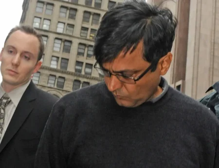 In this Oct. 16, 2009 photo, Anil Kumar is led in handcuffs from FBI headquarters in New York. Kumar and four others including Raj Rajaratnam, billionaire founder of the Galleon Group, a major hedge fund, were arrested with Rajaratnam charged with insider trading in the stock of several companies including Hilton, Clearwire, and Google. © AP Photo/ Louis Lanzano