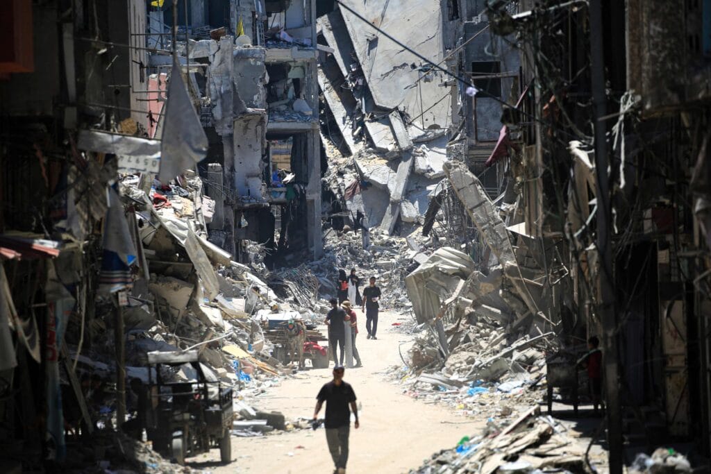 Palestinian men walk along a narrow street past destroyed buildings in Khan Younis, in the southern Gaza Strip, Palestine, June 11, 2024. © AFP Photo