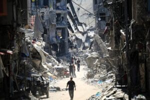 Palestinian men walk along a narrow street past destroyed buildings in Khan Younis, in the southern Gaza Strip, Palestine, June 11, 2024. © AFP Photo