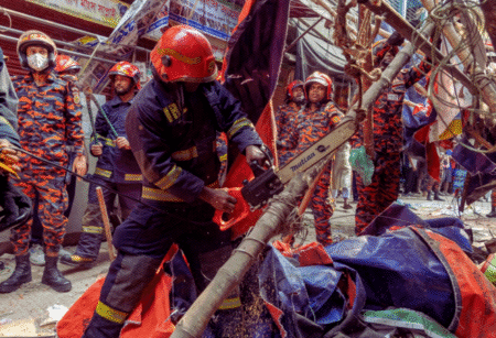 Rescue and fire officials cut building railings falling on the street to make way after an earthquake in Dhaka. © AP