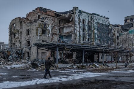 A man walks down a war-ravaged street in Pokrovsk, an industrial city in eastern Ukraine's Donetsk region, on Dec. 19, 2024. Behind him is the hotel Druzhba, which was destroyed by a Russian missile last summer. Pokrovsk was once home to 60,000 people. Now it's largely abandoned, with Russian troops active within a mile of the outskirts. © Anton Shtuka/NPR
