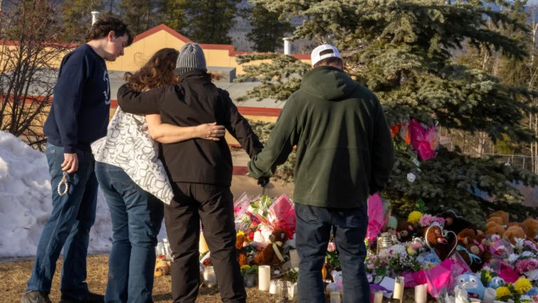 Residents hug as they place flowers at a memorial for the victims of Tuesday’s mass shooting in Tumbler Ridge, British Columbia, Canada, on Thursday, Feb. 12, 2026. (Christinne Muschi/The Canadian Press via AP)